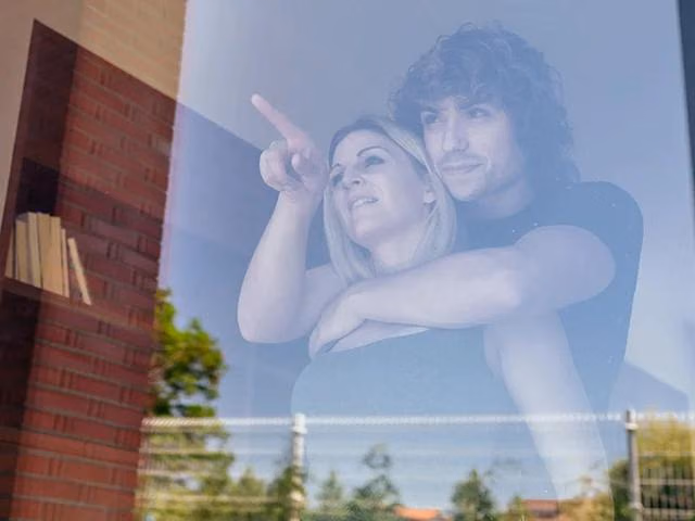 Zwei Personen stehen hinter einem Fenster und blicken nach draußen.