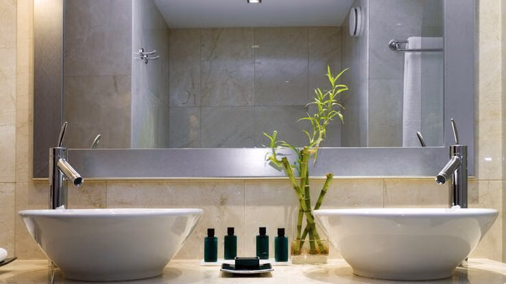 Doppelwaschtisch im Badezimmer mit einem großen Spiegel dahinter.