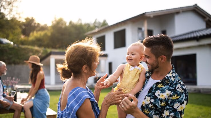 Eine Familie erfreut sich im Garten ihres Neubaus.
