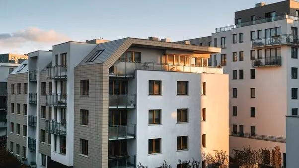 Mehrfamilienhäuser werden von der untergehenden Sonne angestrahlt.