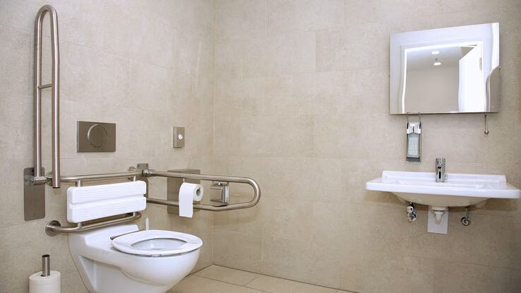 Abgebildet ist ein altersgerechtes Badezimmer mit Handgriffe an der Toilette.