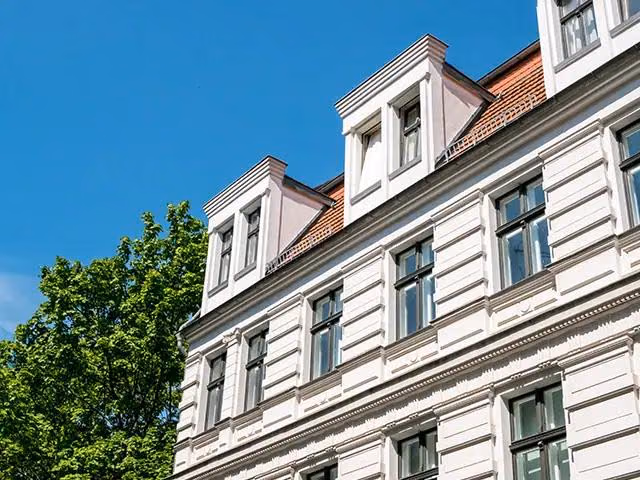 Ausschnitt einer hellen Gebäudefassade mit Gauben