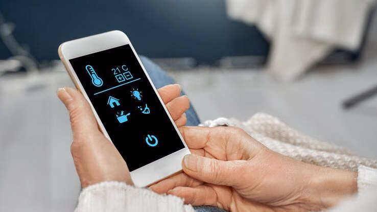Das Foto zeigt ein Smartphone mit einer Smart Home App. Man kann die Temperatur, das Licht, sowie weitere Einstellungen vornehmen.