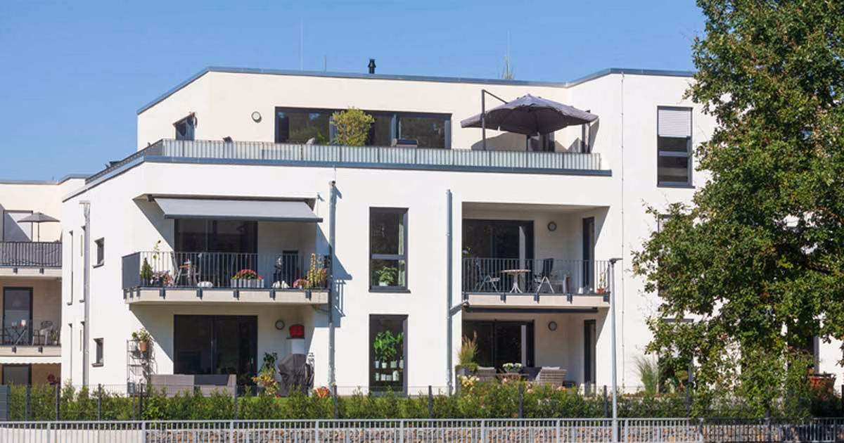 Es ist ein weißes Mehrfamilienhaus zu sehen.