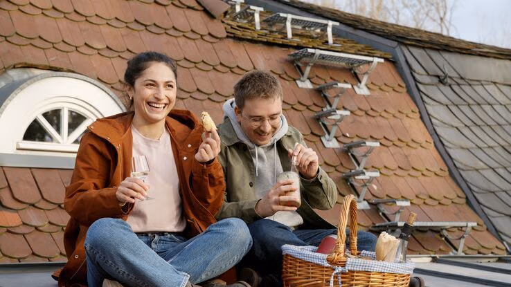 Ein Paar macht auf dem Dach ihres Hauses ein Picknick.