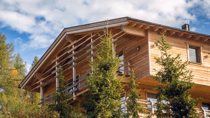 Ein Ökohaus aus Holz ist umgeben von Bäumen.