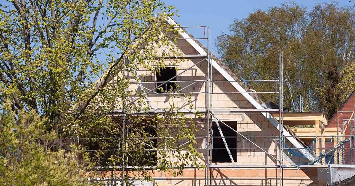 Ein Haus befindet sich in der Bauphase und hat ein Gerüst drum herum.