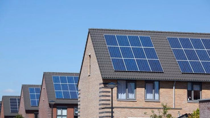 Abgebildet sind mehrere Reihenhäuser mit installierten Photovoltaikanlagen auf den Dächern.