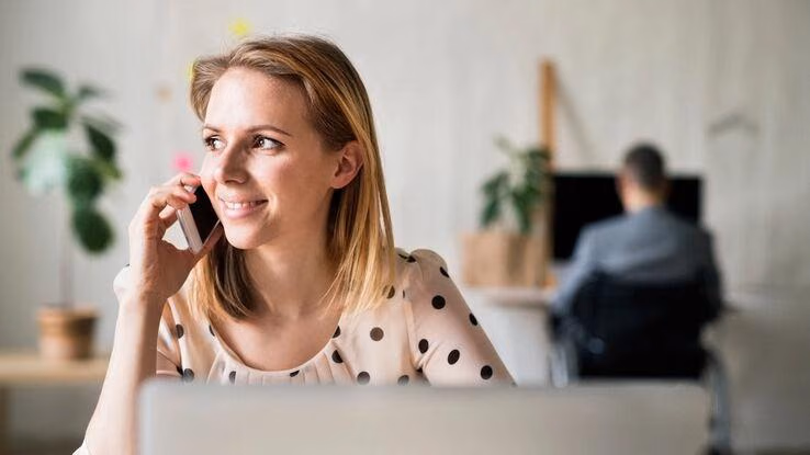 Eine Frau informiert sich am Telefon über Baufinanzierung.