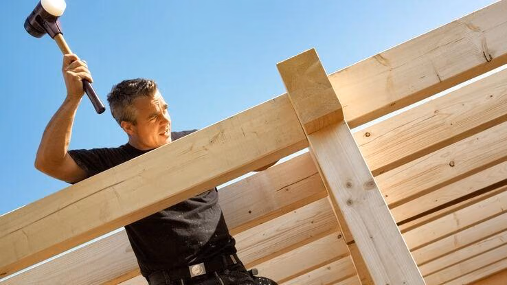 Ein Handwerker macht den Dachstuhl fertig.