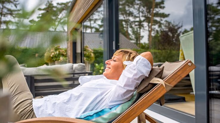 Eine Frau entspannt auf der Terrasse ihrer Ferienwohnung.