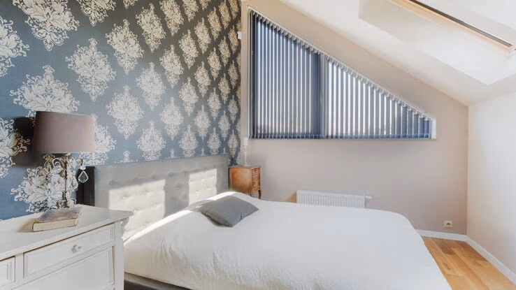 Ein Schlafzimmer mit Bett und Kommode unter einer Dachschräge.