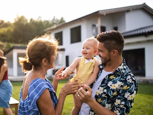 Mehrere Personen im Garten vor einem Einfamilienhaus.