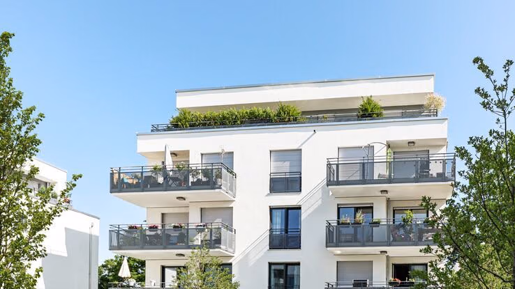 Abgebildet ist ein modernes Wohnhaus mit Balkonen.