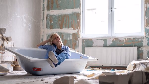 Ein Badezimmer wird renoviert. Eine Frau sitzt in einer ausgebauten Badewanne.