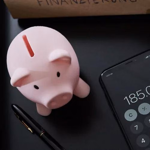 Ein Sparschwein neben einem Taschenrechner.
