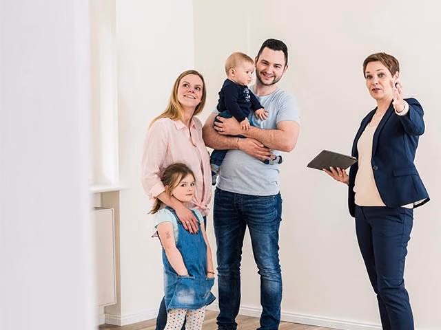 Eine Immobilienmaklerin zeigt einer Familie mit 2 Kindern eine Wohnung.