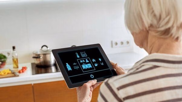 Eine Frau hält ein Tablet in der Hand, mit dem sie verschiedene Einstellungen im Haus treffen kann.