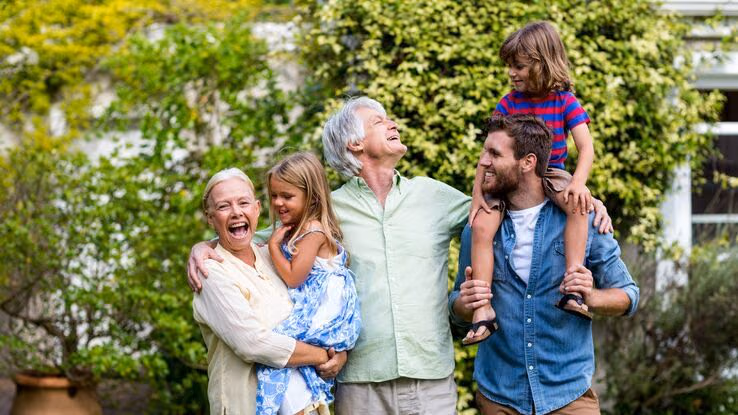 Das Foto zeigt eine Familie in ihrem Garten. Es sind zwei Kinder, der Vater, sowie die Großeltern zu erkennen.