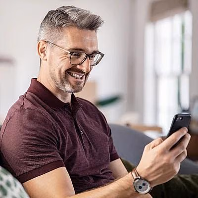 Ein Mann nutzt sein Smartphone und erkundigt sich zum Thema Baufinanzierung.