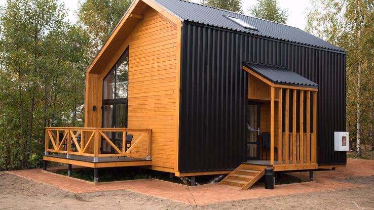 Ein Tiny House steht auf einem Grundstück umgeben von Bäumen.