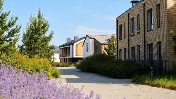 Verschiedene moderne Häuser hintereinander. Links im Bild sind Bäume und Lavendel.