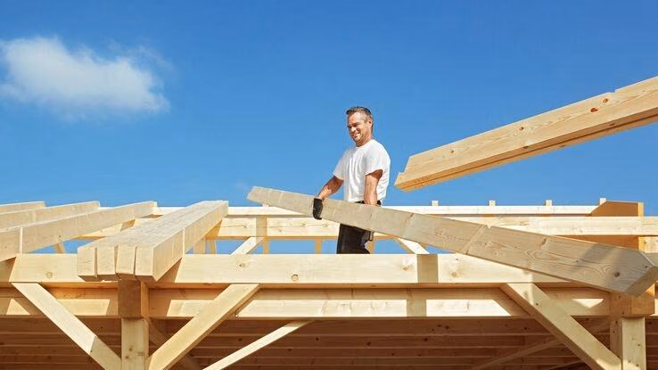 Abgebildet ist ein Handwerker bei den Dacharbeiten bei einem Neubau