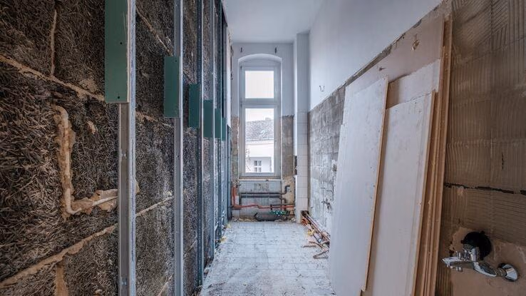 Ein Zimmer während der Sanierung. Die Kacheln wurden entfernt und man erkennt die Dämmung an der linken Wand.