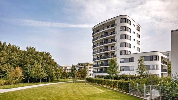 Ein Mehrfamilienhaus mit einem kleinen Park davor.