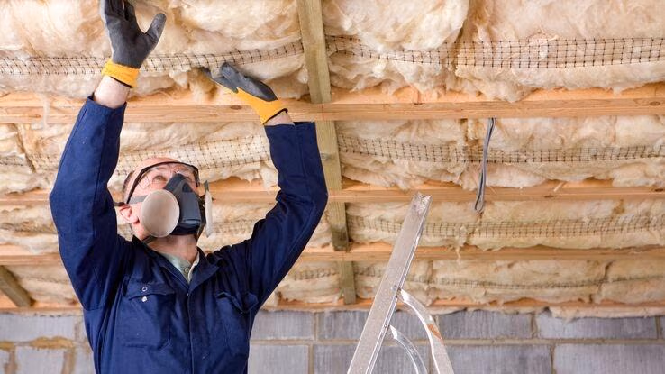 Abgebildet ist ein Handwerker beim dämmen.