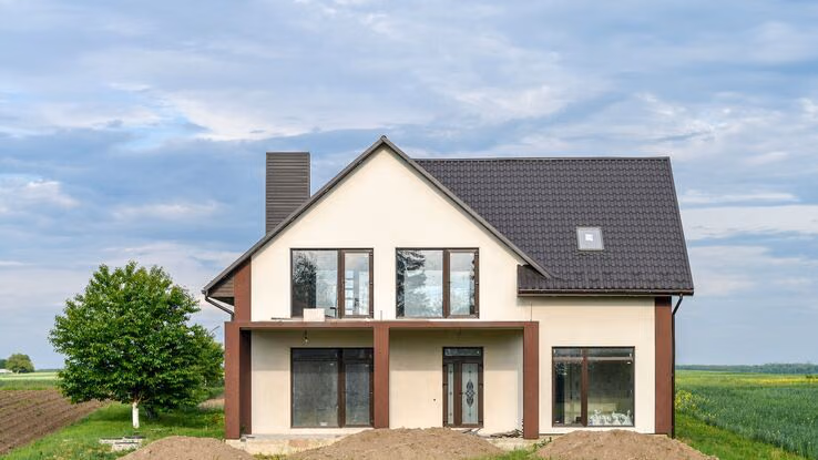 Abgebildet ist ein Passivhaus mit dunklem Dach in einer ländlichen Umgebung.