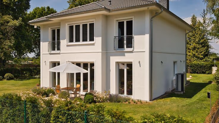 Ein Einfamilienhaus mit speziellem Baustil ist umgeben von einem Garten.