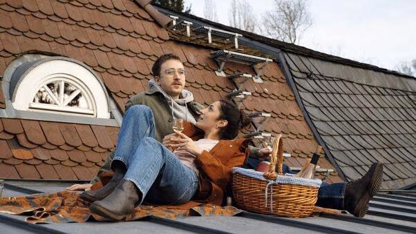 Ein Pärchen ist erleichtert nach Fertigstellung des Hauses und feiert auf dem Dach.