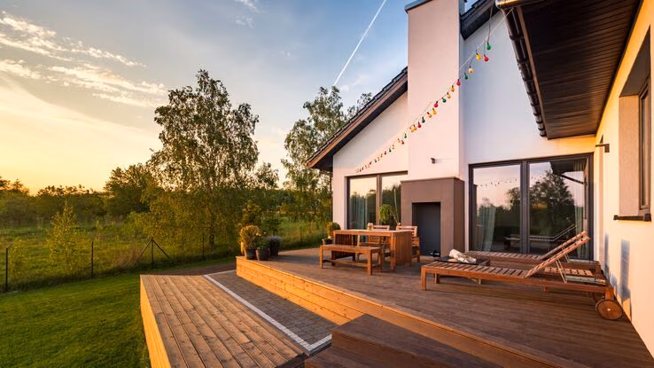 Holzterrasse mit Möbeln im Sonnenuntergang.