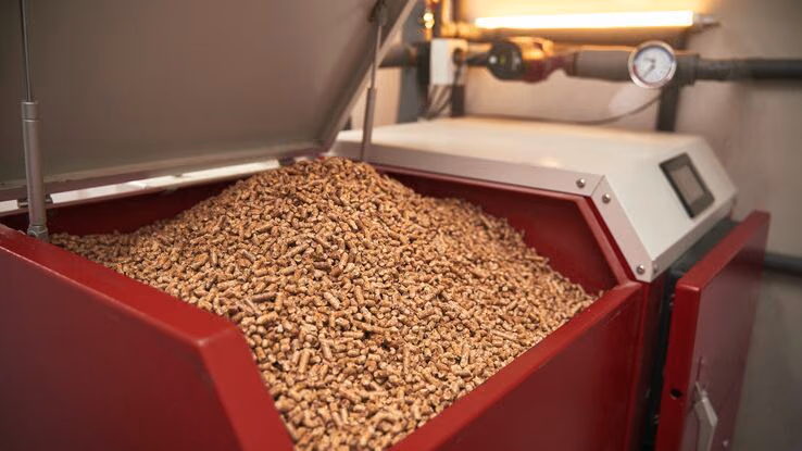 Abgebildet sind Holzpellets in einem großen roten Behälter.