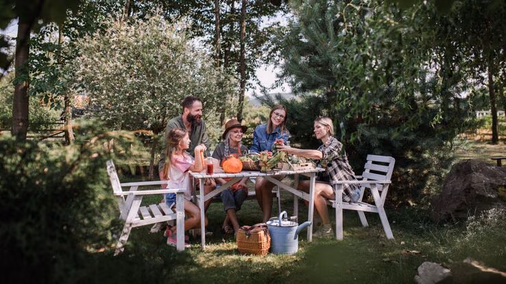 Eine Familie sitzt an einem Tisch in ihrem Garten zusammen.