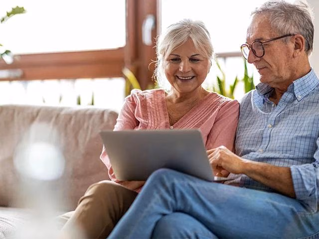 Ein ältere Pärchen informiert sich zum Thema altersgerechte Modernisierung an ihrem Laptop.