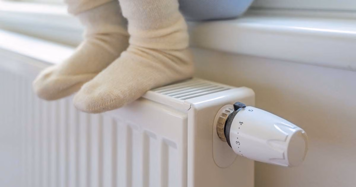Eine Person sitzt auf einer Fensterbank und hat die Füße auf einer Heizung.