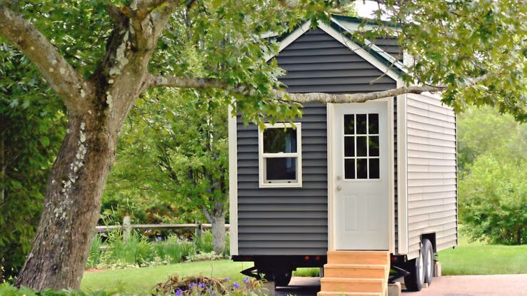 Ein Tiny House auf Rädern steht in einer grünen Landschaft.