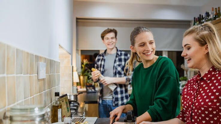 WG-Mitbewohner kochen gemeinsam in der Küche während sie sich gut unterhalten.
