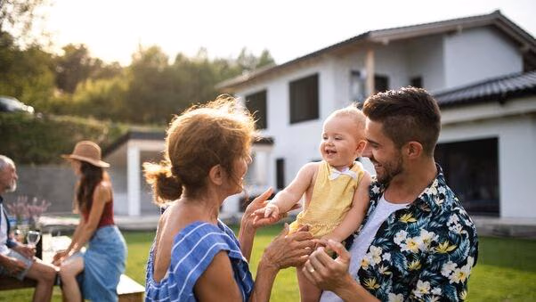 Mehrere Generationen treffen sich im Garten und feiern ein Familienfest.