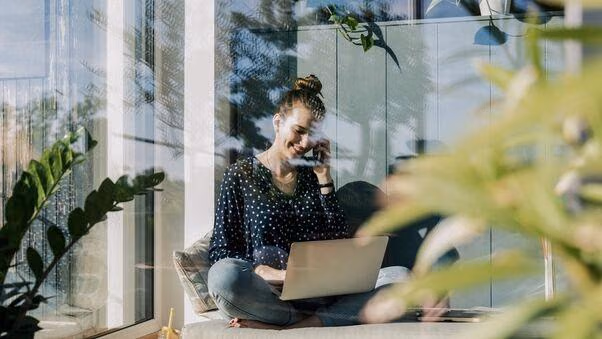 Eine Frau sitzt an ihrem Laptop und informiert sich über nachhaltiges Wohnen.