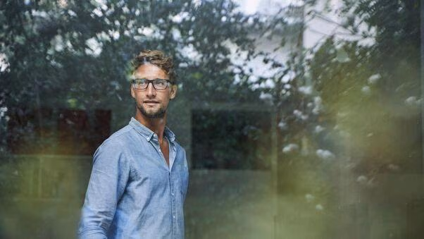 Ein Mann schaut aus dem Fenster seiner Immobilie nach draußen.