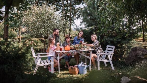 Eine Familie sitzt in ihrem garten am Tisch und isst.