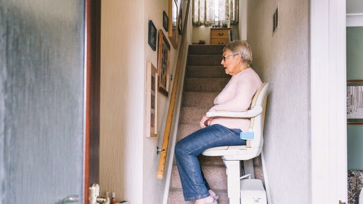 Eine Frau nutzt den Treppenlift nach oben in den ersten Stock.