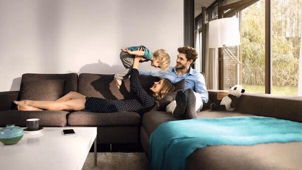 Eine junge Familie sitzt auf ihrer Couch und genießen die Zeit in ihrem Mietshaus.