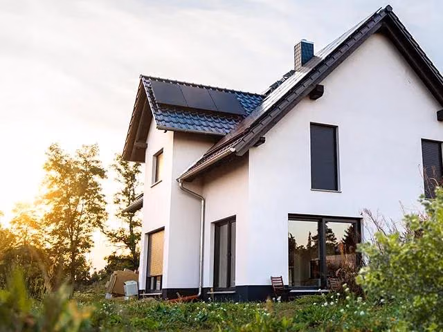 Ein neugebautes Haus mit Spitzdach im Grünen.
