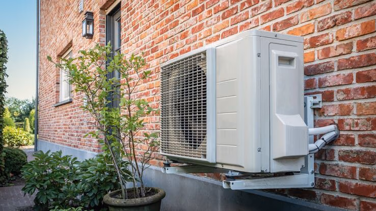 Abgebildet ist eine nachgerüstete Wärmepumpe an der Hauswand.