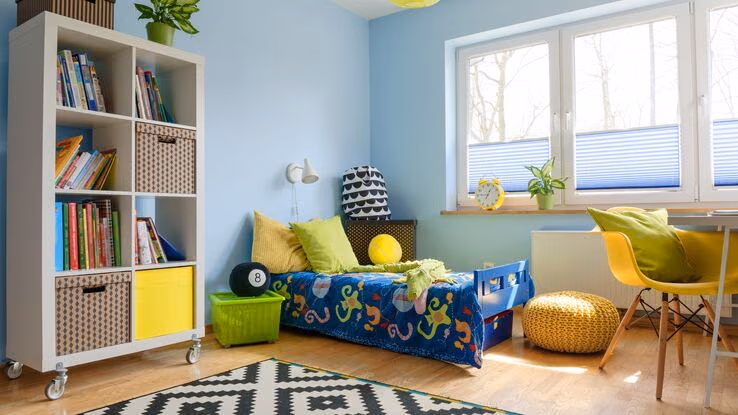 Ein buntes Kinderzimmer mit einem Bett, einem Regal auf Rädern und einem Schreibtisch.