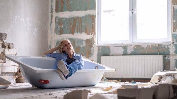 Eine Frau modernisiert ihr Badezimmer und sitzt in einer noch zu montierenden Badewanne.